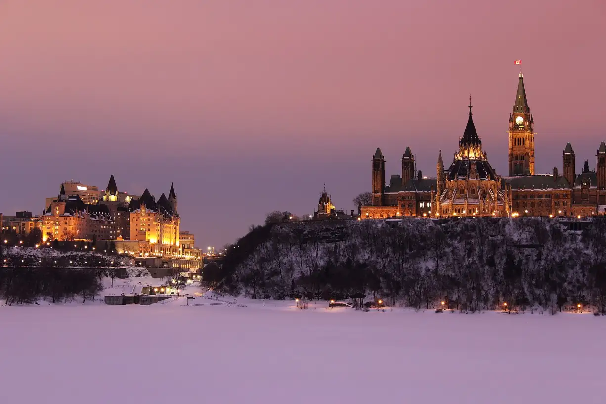 Parliament Hill and the Château Laurier above the frozen Ottawa River at dusk